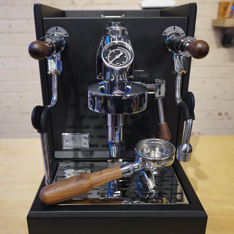 Espresso machine with wooden handles on a wooden surface.