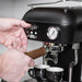 Person using an espresso machine with two cups on a light background