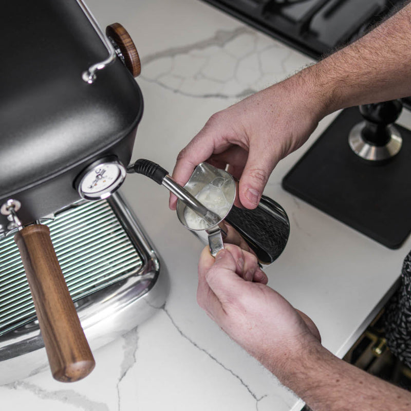 Person using a manual espresso machine with a focus on the portafilter and hand action.